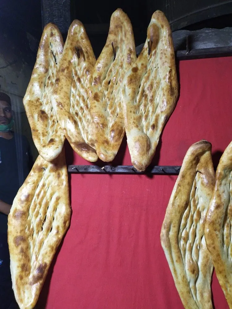Fresh Afghan naan loaves hanging on a rail at a bakery