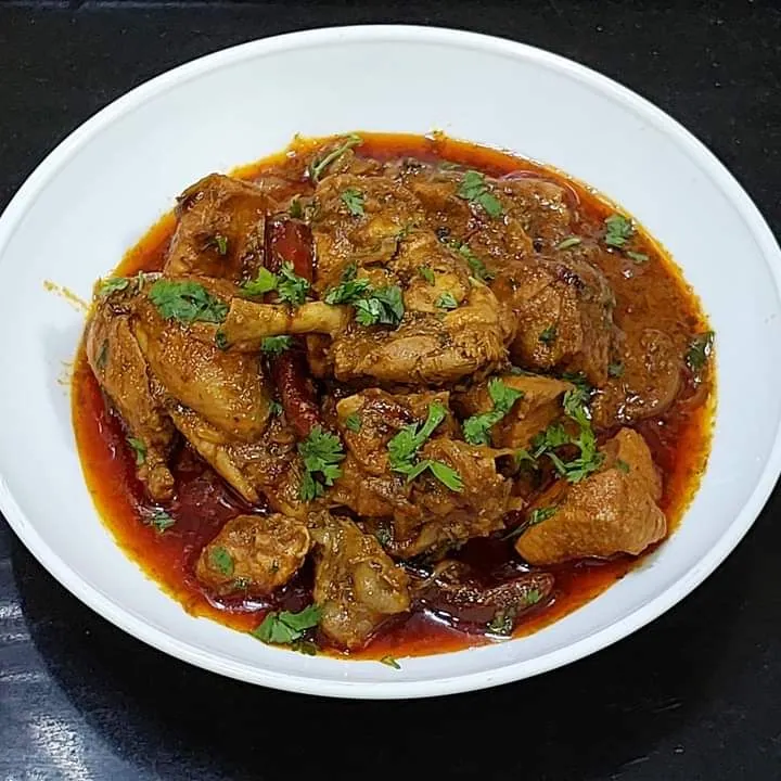 A plate of chicken qorma in a spiced tomato sauce, garnished with coriander