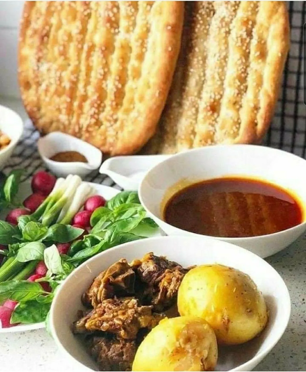 A bazaar-style spread of shorwa broth with meat and potatoes, herbs, radishes, and naan