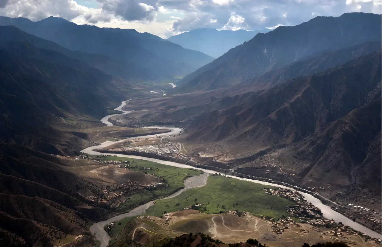 The Kunar River winding through a wide green valley between steep mountains, with villages along its banks