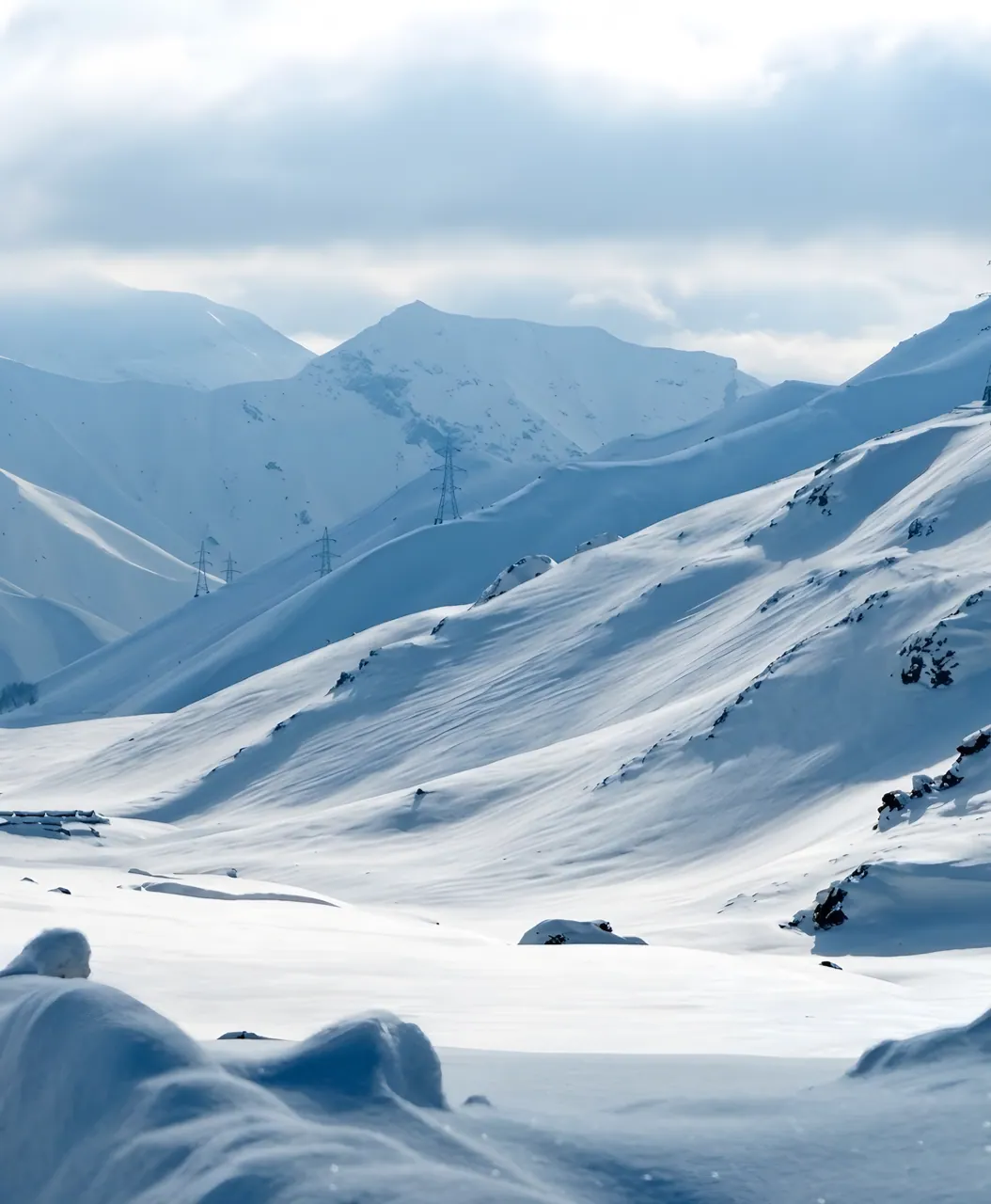 Snow-covered mountain slopes under a cloudy sky on the way over the Salang Pass