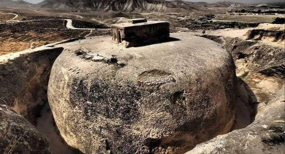 The Takht-e Rostam stupa, a dome carved out of the bedrock, standing in its round trench near Aybak