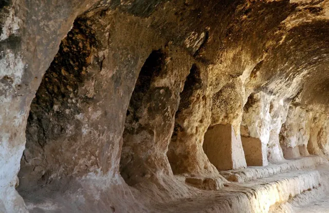 A corridor carved into the rock, with cell openings along one side, in the Buddhist cave monastery in Samangan